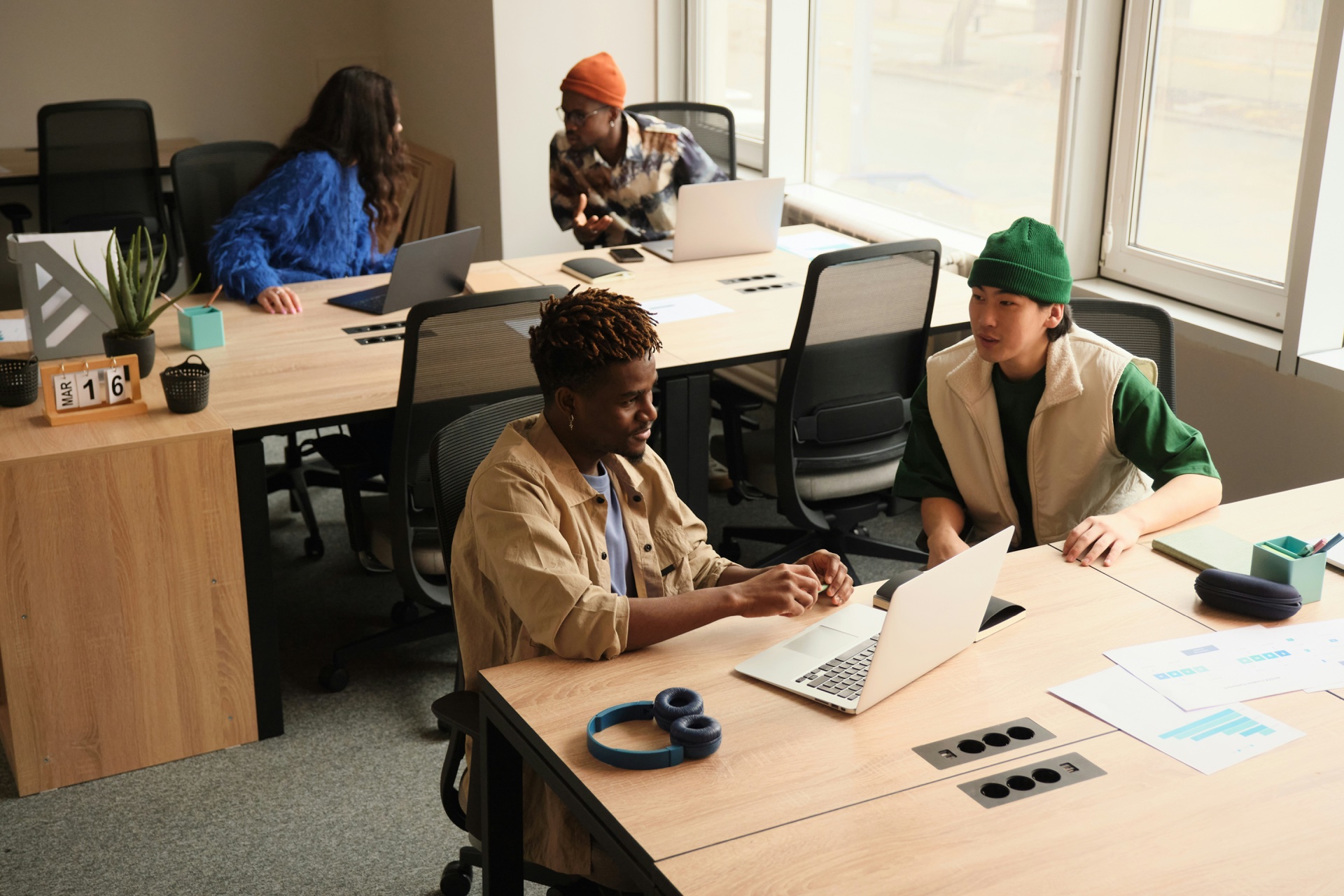 A team talking and working together in a sunlit shared office.