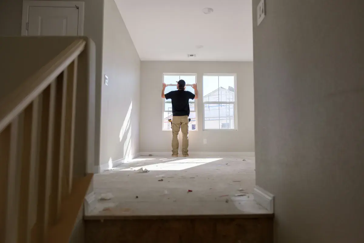 Worker standing in an unfinished room during a renovation