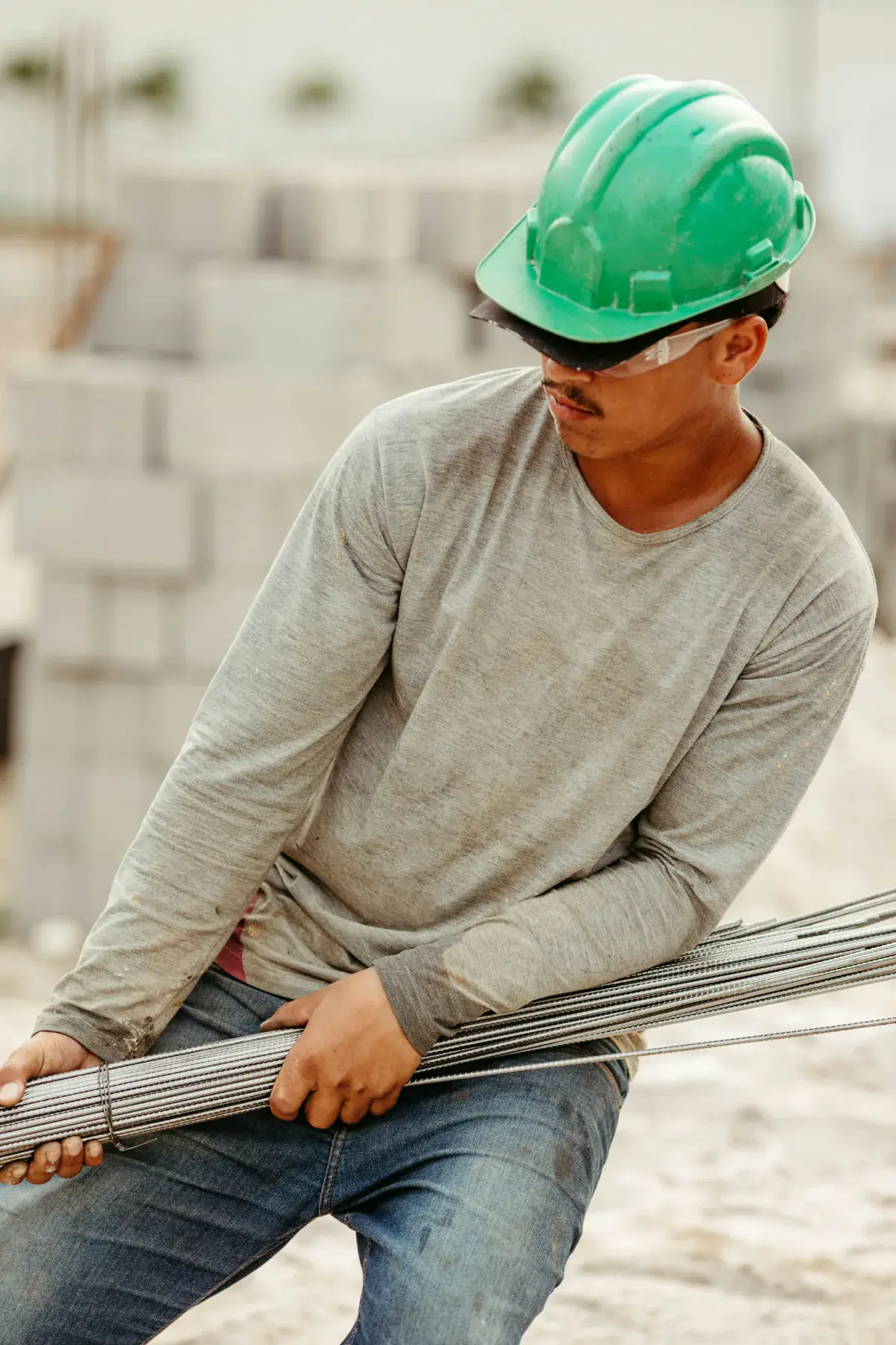 Construction worker in a green hard hat carrying rebar