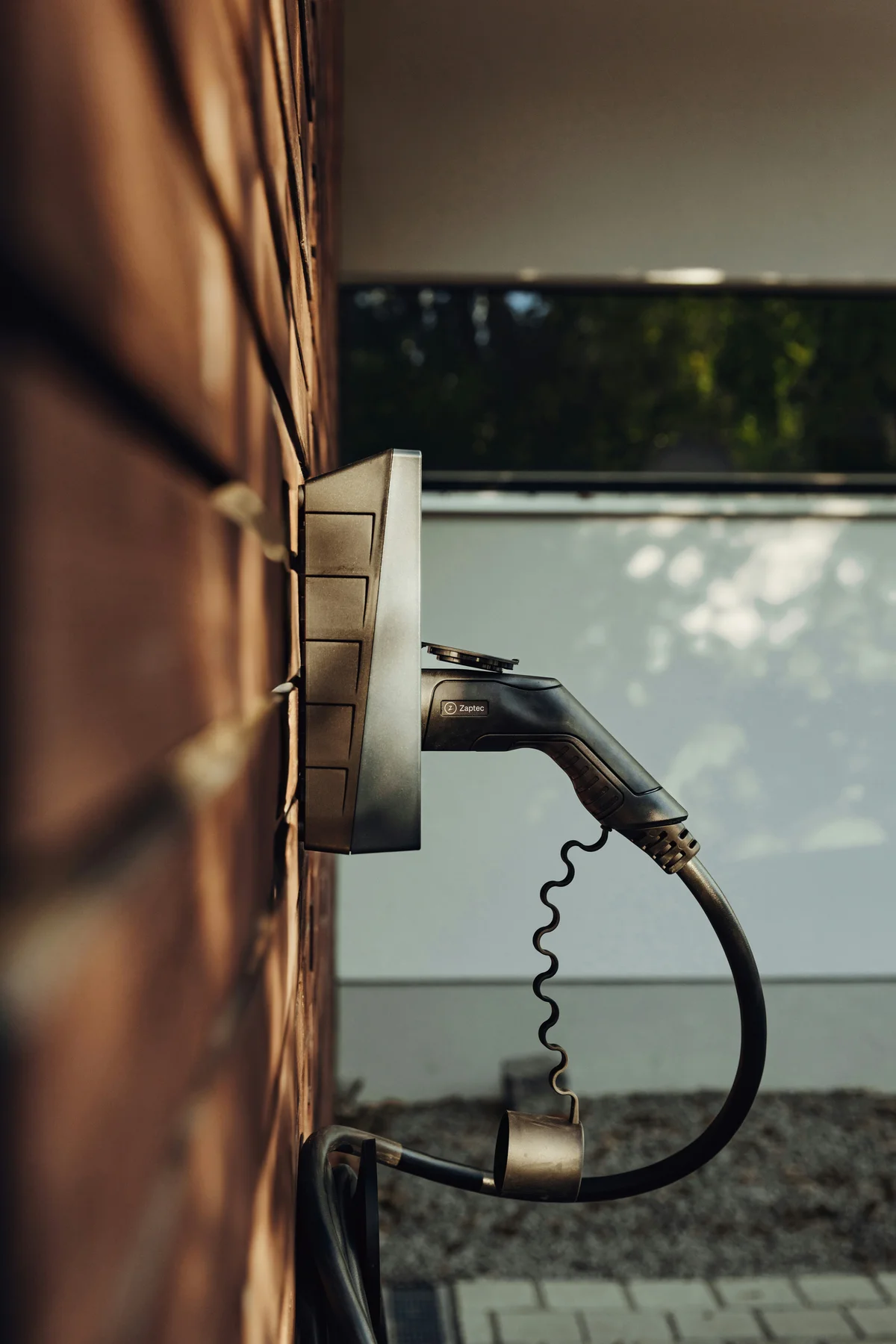 Wall-mounted electrical charging unit with its cable