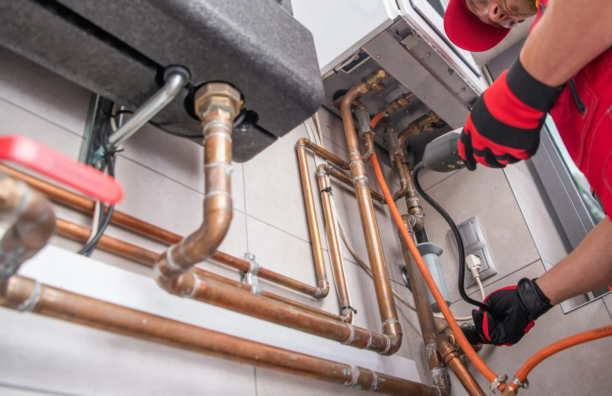 Plumber tightening copper pipes under a sink