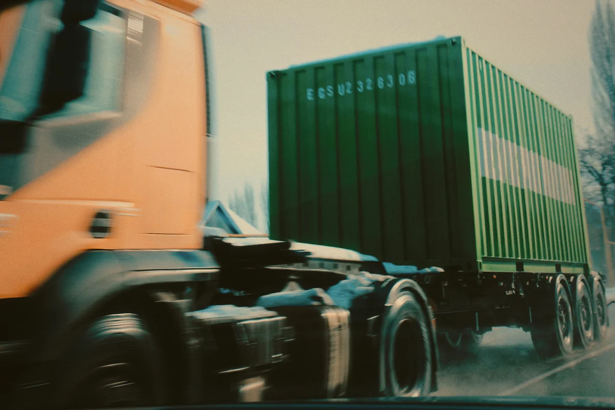 Truck pulling a green shipping container on the highway